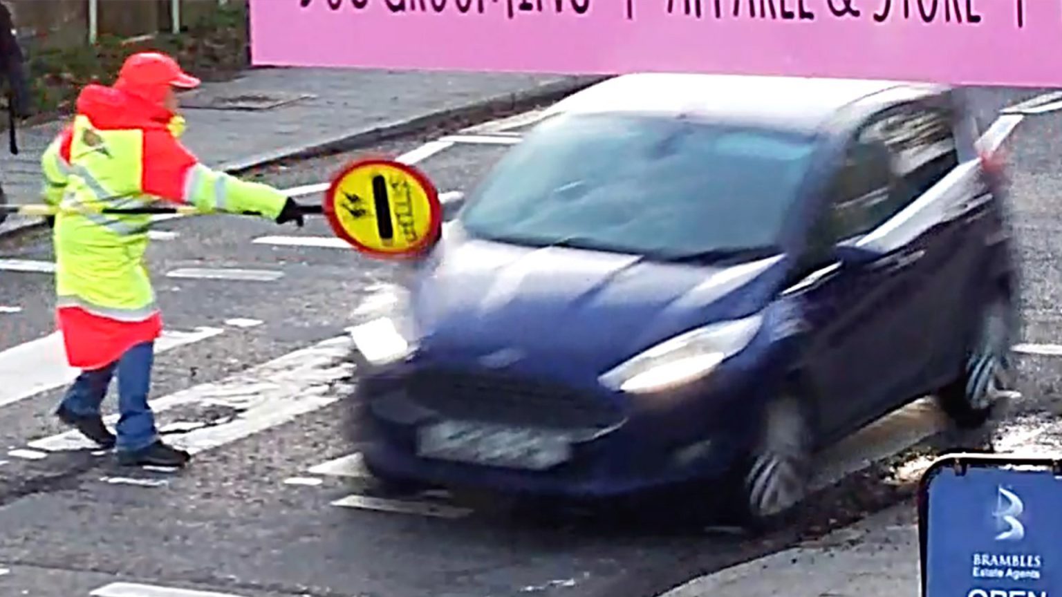 Fiesta driver ignores the lollipop lady as he drives through zebra crossing smashing into his sign Watch as Fiesta driver ignores lollipop lady and drives through zebra crossing smashing into her sign
